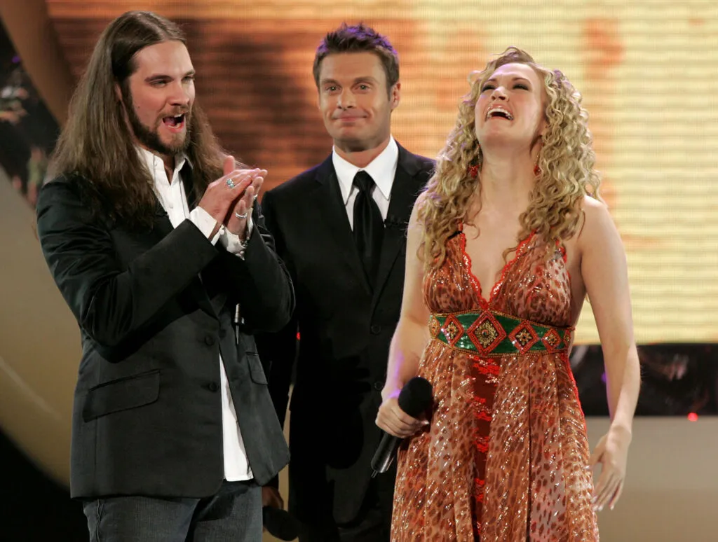 Carrie Underwood Loves Beyonce—Carrie in 2005, the moment she learned she won American Idol. She is wearing an orange dress and is with Ryan Seacrest and Bo Bice. 